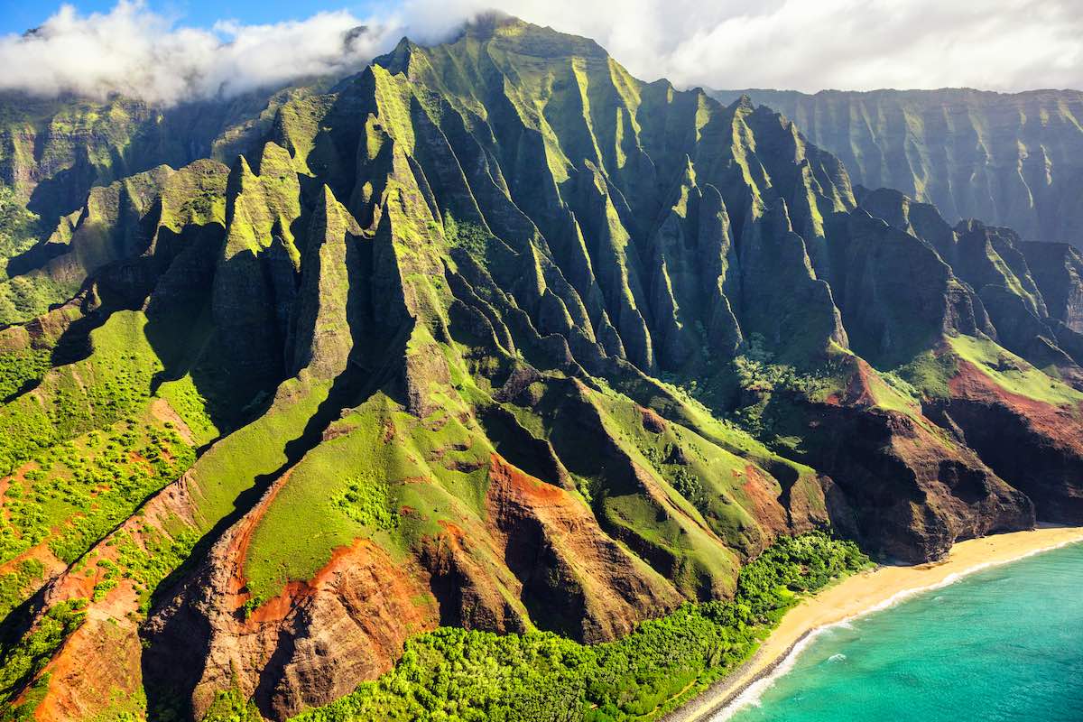 Find out the Best Island to Visit in Hawaii according to top Hawaii travel blog Hawaii Travel Guides. Image of Hawaii nature travel destination. Na Pali coast on Kauai island. Helicopter aerial view of Na Pali Coast mountain landscape in Kauai island, Hawaii, USA.