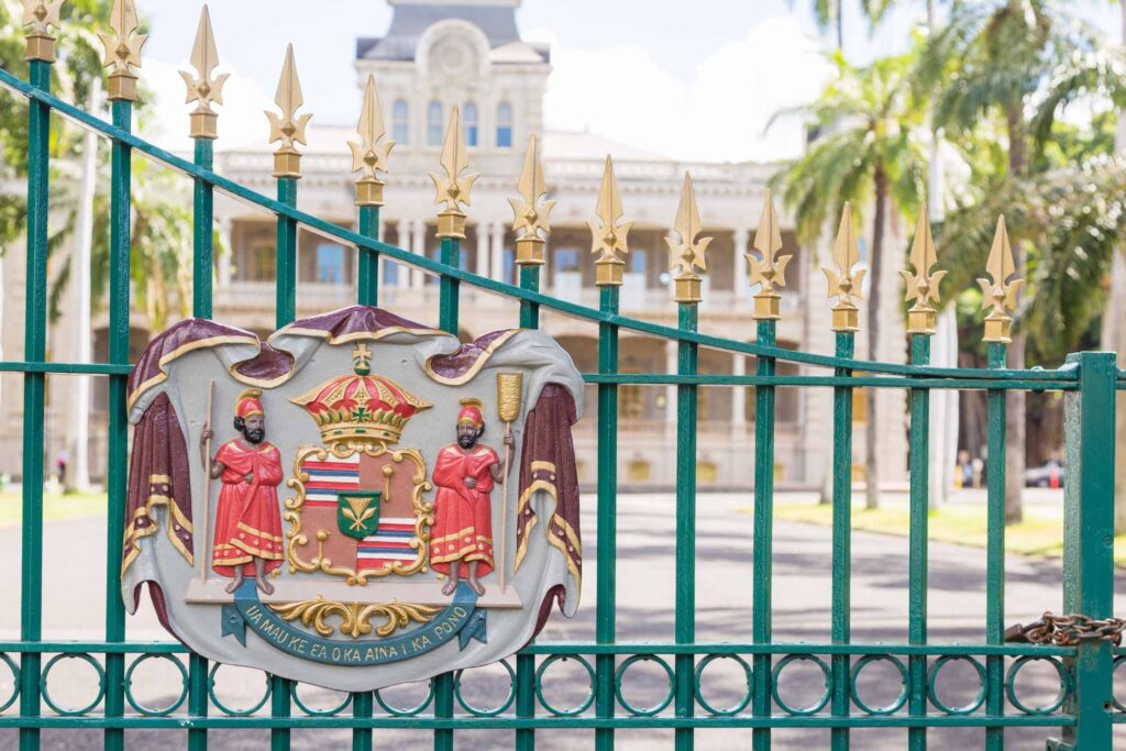 Emblem showing indigenous people and insignia of Hawaii at the gate of Iolani Palace in Honolulu, Hawaii, USA